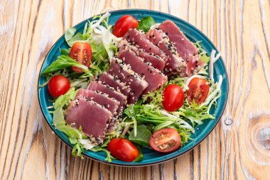 Çiğ ton balığı, susam ve vişneli domates fotoğraflı salata. Kırsal arkaplanda üst görünüm