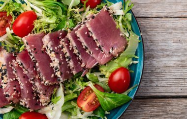 Çiğ ton balığı, susam ve vişneli domates fotoğraflı salata. Kırsal arkaplanda üst görünüm