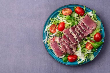 Çiğ ton balığı, susam ve vişneli domates fotoğraflı salata. Kırsal arkaplanda üst görünüm