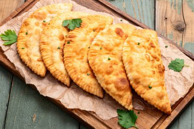 Atıştırmalık çizelgeler. Et fotoğrafçılığı yapan börekler. Kırsal arkaplanda üst görünüm