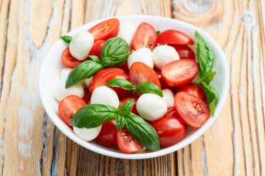 Fesleğen yaprakları, kiraz domatesleri ve mozzarella peyniri. Kase yemek fotoğrafçılığında. Üst görünüm