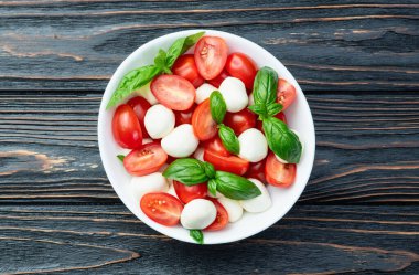 Fesleğen yaprakları, kiraz domatesleri ve mozzarella peyniri. Kase yemek fotoğrafçılığında. Üst görünüm