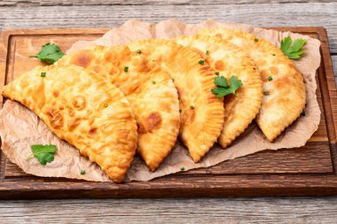 Atıştırmalık çizelgeler. Et fotoğrafçılığı yapan börekler. Kırsal arkaplanda üst görünüm