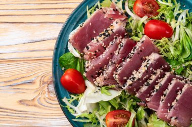 Çiğ ton balığı, susam ve vişneli domates fotoğraflı salata. Kırsal arkaplanda üst görünüm