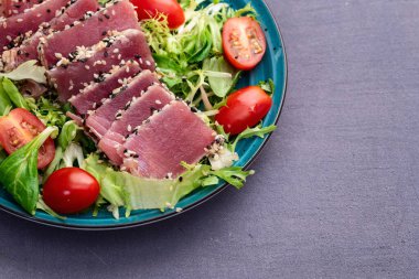 Çiğ ton balığı, susam ve vişneli domates fotoğraflı salata. Kırsal arkaplanda üst görünüm