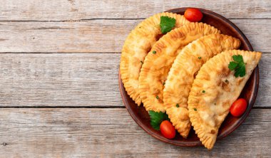 Atıştırmalık çizelgeler. Et fotoğrafçılığı yapan börekler. Kırsal arkaplanda üst görünüm