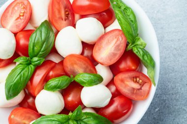 Fesleğen yaprakları, kiraz domatesleri ve mozzarella peyniri. Kase yemek fotoğrafçılığında. Üst görünüm