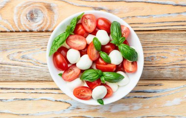 Fesleğen yaprakları, kiraz domatesleri ve mozzarella peyniri. Kase yemek fotoğrafçılığında. Üst görünüm