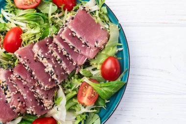 Çiğ ton balığı, susam ve vişneli domates fotoğraflı salata. Kırsal arkaplanda üst görünüm
