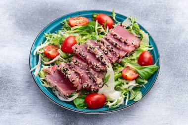 Çiğ ton balığı, susam ve vişneli domates fotoğraflı salata. Kırsal arkaplanda üst görünüm