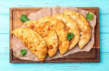 Atıştırmalık çizelgeler. Et fotoğrafçılığı yapan börekler. Kırsal arkaplanda üst görünüm