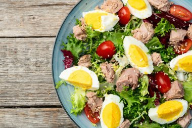 Yumurta ve domates fotoğraflı konserve ton balığı salatası. Kırsal arkaplanda üst görünüm
