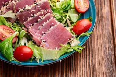 Çiğ ton balığı, susam ve vişneli domates fotoğraflı salata. Kırsal arkaplanda üst görünüm