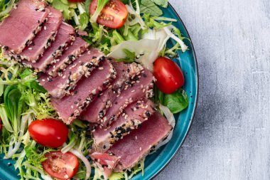 Çiğ ton balığı, susam ve vişneli domates fotoğraflı salata. Kırsal arkaplanda üst görünüm
