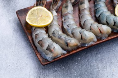 Çiğ büyük kaplan (kral) karidesleri temizler, soyarlar ve biçerdöverler. Kırsal arkaplanda üst görünüm