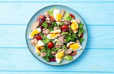 Yumurta ve domates fotoğraflı konserve ton balığı salatası. Kırsal arkaplanda üst görünüm