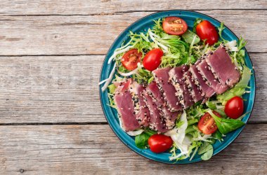 Çiğ ton balığı, susam ve vişneli domates fotoğraflı salata. Kırsal arkaplanda üst görünüm