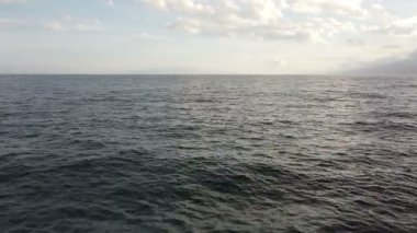 Ufukta uzak bir kasabanın olduğu sakin bir deniz manzarası. Fırtına bulutları gökyüzünde toplanıyor ve dramatik ve huzurlu bir atmosfer yaratıyor..