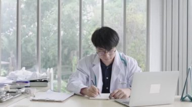 Asyalı erkek çocuk doktoru hastalara tavsiye veriyor, genç Asyalı erkek doktor ise kadın hastalara danışmanlık yapıyor ve hastane, sağlık ve yardım konseptine başvuruyor.