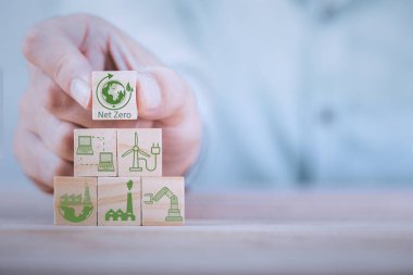 Businessman hand arranging wood block with net zero icon , Net zero by 2050 Carbon neutral energy or Net Zero greenhouse gas emission target on wooden cubes background