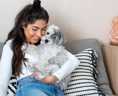 Güzel genç bir kadın, Beyaz kıdemli Havan Köpeğine sarılıyor. 