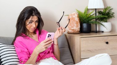 Surprised Woman Sitting at Home Looking her Smartphone