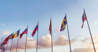 National flags in a row against sunset blue sky with clouds