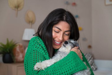 Güzel genç bir kadın, Beyaz kıdemli Havan Köpeğine sarılıyor.