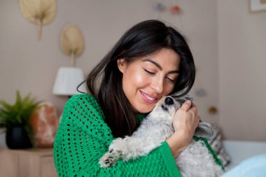 Güzel genç bir kadın, Beyaz kıdemli Havan Köpeğine sarılıyor.