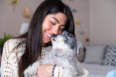 Güzel genç bir kadın, Beyaz kıdemli Havan Köpeğine sarılıyor.