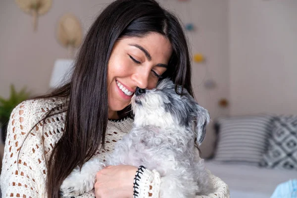 Güzel genç bir kadın, Beyaz kıdemli Havan Köpeğine sarılıyor.