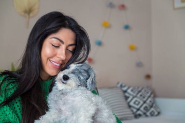 Güzel genç bir kadın, Beyaz kıdemli Havan Köpeğine sarılıyor.