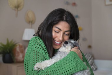 Güzel genç bir kadın, Beyaz kıdemli Havan Köpeğine sarılıyor.