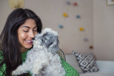 Güzel genç bir kadın, Beyaz kıdemli Havan Köpeğine sarılıyor.