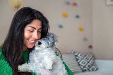 Güzel genç bir kadın, Beyaz kıdemli Havan Köpeğine sarılıyor.