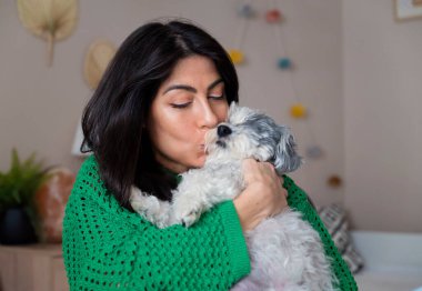 Güzel genç bir kadın, Beyaz kıdemli Havan Köpeğine sarılıyor.