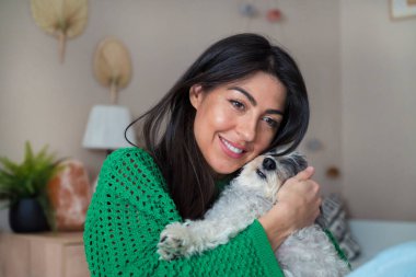 Güzel genç bir kadın, Beyaz kıdemli Havan Köpeğine sarılıyor.