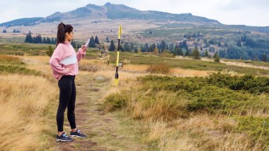 Young Woman using mobile phone in the Mountain .Woman using trail map in the mountain