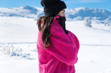 Young woman in the cold winter mountain trying to warm herself. Winter concept