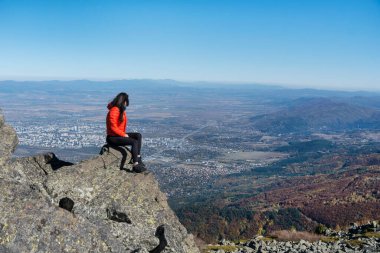 Sofya kentinin yukarısındaki sonbahar dağında yüksek bir kayada oturan bir kadın. Vitoşa Dağı, Bulgaristan
