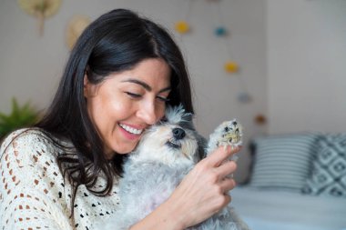 Güzel genç bir kadın, Beyaz kıdemli Havan Köpeğine sarılıyor.