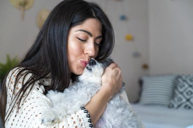 Güzel genç bir kadın, Beyaz kıdemli Havan Köpeğine sarılıyor.