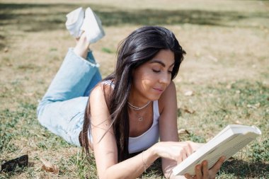 Yaz parkında kitap okuyan kadın.
