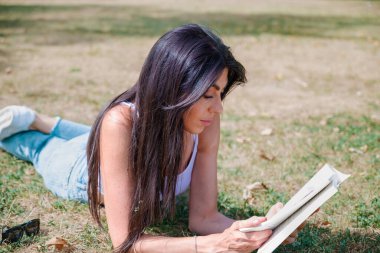 Yaz parkında kitap okuyan kadın.