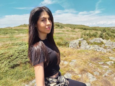 Yaz dağının zirvesinde oturan muhteşem manzaralı bir kadın.