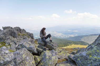 Yaz dağının zirvesinde oturan muhteşem manzaralı bir kadın.