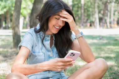 Güzel Esmer Kadın yaz parkında telefonunu kullanıyor.