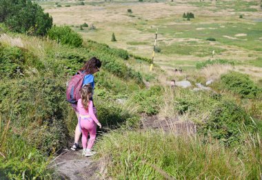 Anne ve küçük çocuk dağda yürüyor. Doğada Aile Zamanı.