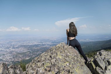 Sofya şehrinin yukarısındaki yaz dağında kayalarda oturan bir kadın.