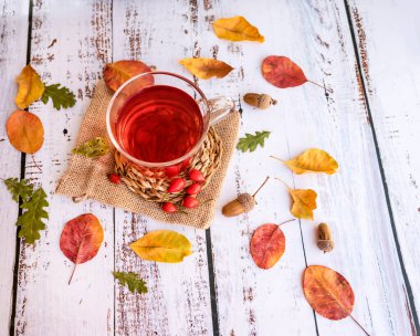 Sonbahar yaprakları sonbahar mevsimi konseptiyle beyaz ahşap arka planda gül çayı